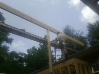 Carpenter setting a ridge beam over a new addition frame — Ice Dam Removal by Roofing Brothers in Seville