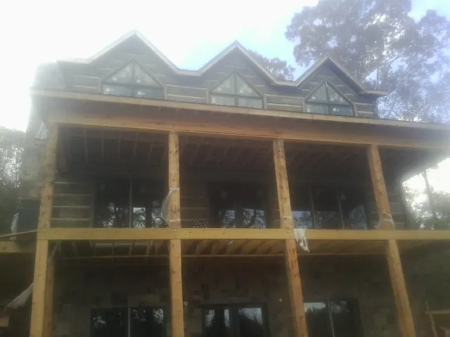 Dormers and porch framing on a large log home under construction — Roof Coating work by our crew in Seville