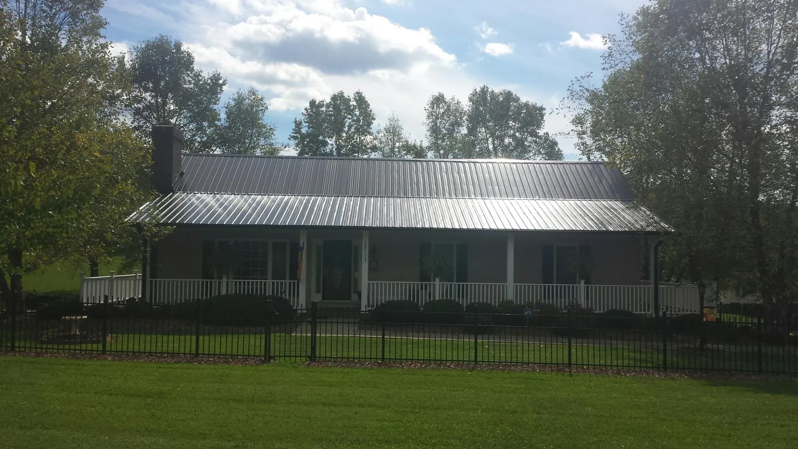 Gray metal roof on a brick ranch with a full width front porch — Gutter Guard Installation work by our crew in Seville