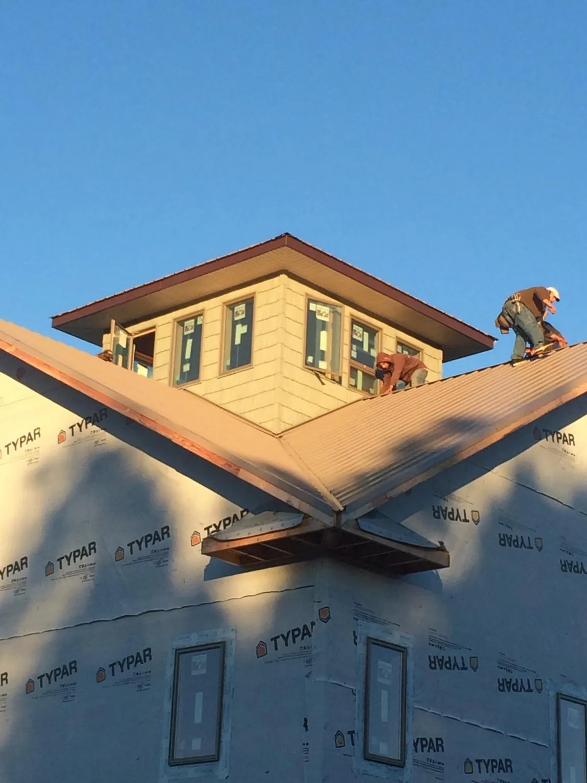 Roofers working around a rooftop cupola on a new metal roof at sunset — Roof Waterproofing in Seville by Roofing Brothers